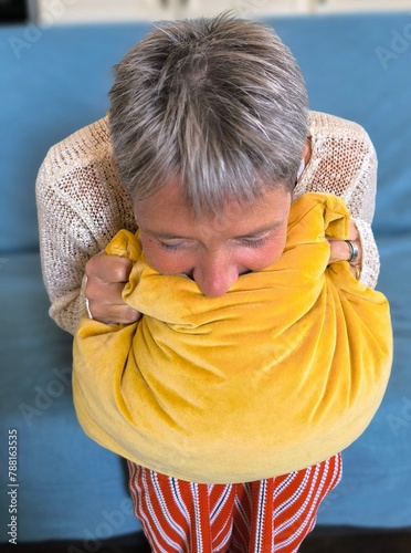 Foto Woman in the foreground, sitting, with her head bowed on a pillow that she holds tightly with her hands