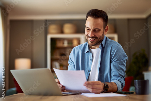 A smiling young adult man reading his resume before applying for a new job.