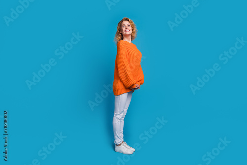 Full length photo of cheerful lovely nice woman wear trendy orange clothes look empty space isolated on blue color background