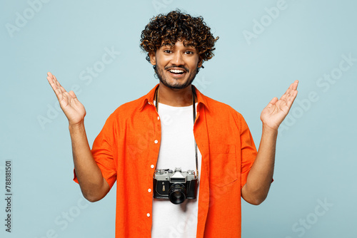 Traveler surprised shocked Indian man wear orange casual clothes spread hands isolated on plain blue background. Tourist travel abroad in free spare time rest getaway. Air flight trip journey concept. photo