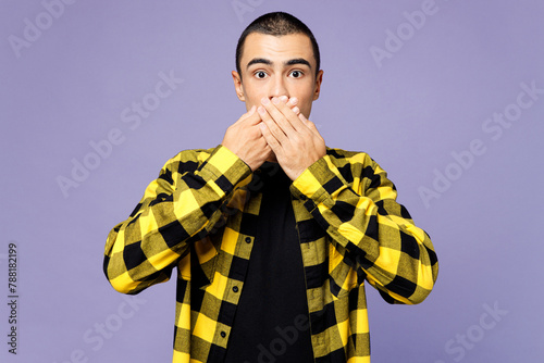 Young shocked surprised sad middle eastern man wear yellow shirt casual clothes cover mouth with hands look camera isolated on plain pastel light purple background studio portrait. Lifestyle concept.