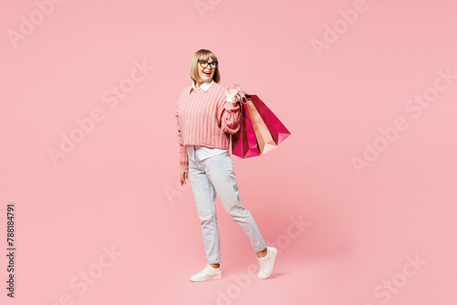 Full body elderly happy fun young woman wear casual clothes hold in hand paper package bags after shopping look aside isolated on plain light pastel pink background. Black Friday sale buy day concept.