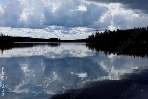 Nature scene with dark forest and lake surface a reflection of the sky at Nurmiselkä lake in cloudy spring weather, Hossa National Park, Suomussalmi, Finland. photo