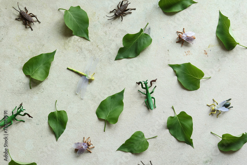 Green leaves and toy insect on old paper background. Flat lay.