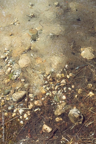 Closeup of stones on the shore of a lake with water fozen in spring. photo