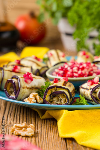 Delicious appetizer of grilled eggplants. Wrapped in rolls with nut paste. Served with pomegranates.