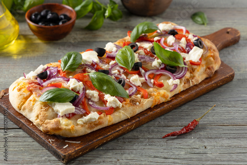 Traditional Roman pinsa with feta cheese, peppers and black olives.