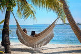 man working on laptop computer while relaxing in beach hammock, freelance worker, remote job via internet