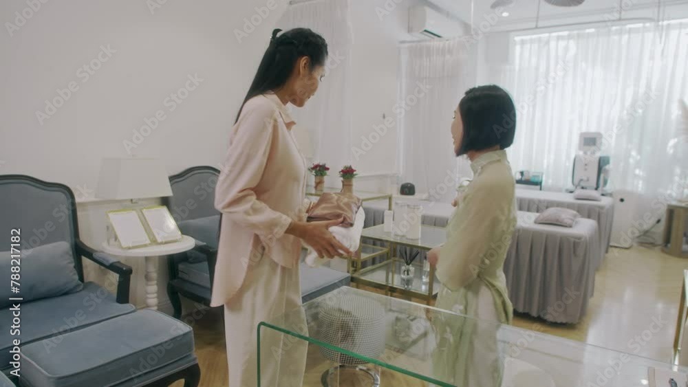 Medium long shot of cheerful receptionist meeting female client in modern spa salon Medium long shot of cheerful receptionist meeting female client in modern spa salon
