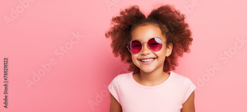 Happy smiling African kid girl with curly hair wearing sunglasses on pink studio background © rohappy