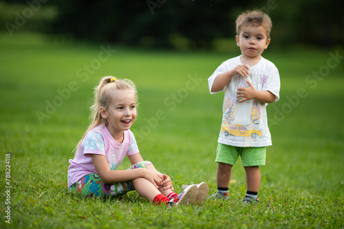 children sitting on the grass, kids playing in the garden, childhood, brother and sister playing together, baby drinking water