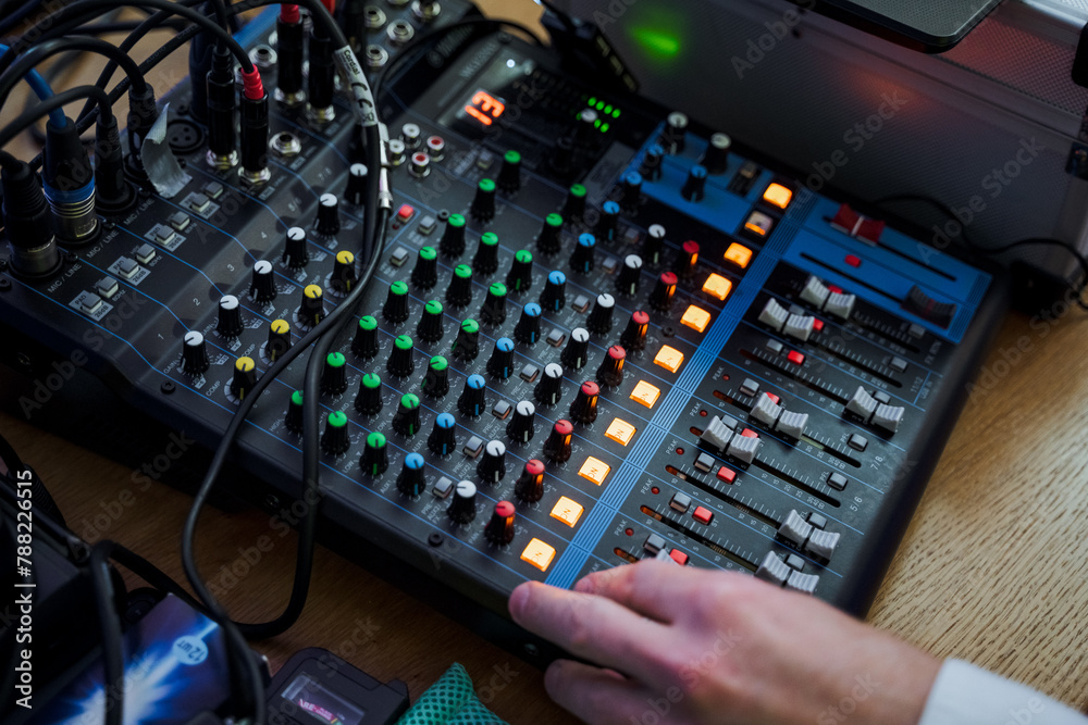Person using mixer on wooden table with audio equipment Person using mixer on wooden table with audio equipment