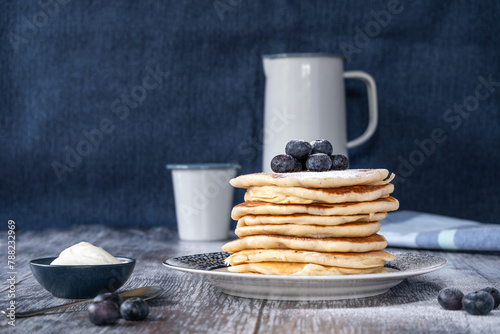 Straigh on view of a stack of pancakes with icing sugar and blueberries