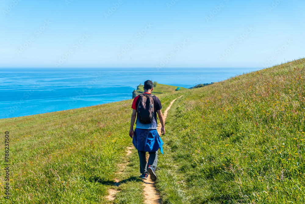 A hiker walking along a coastal path near the Zumaia flysch, Gipuzkoa. Basque Country