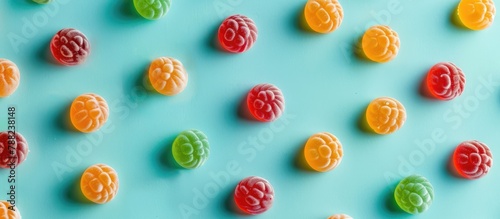 Colorful candies arranged on a soft turquoise background, captured from a top view in a flat lay style.