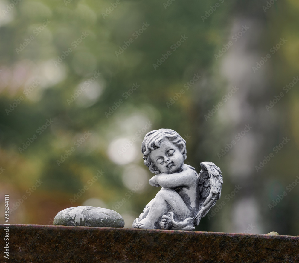 Kleiner sitzender Engel auf Stein vor soften Hintergrund Kleiner sitzender Engel auf Stein vor soften Hintergrund