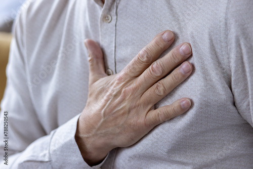 Close-up of a man's hand on his chest feeling heartbeat © Tetiana