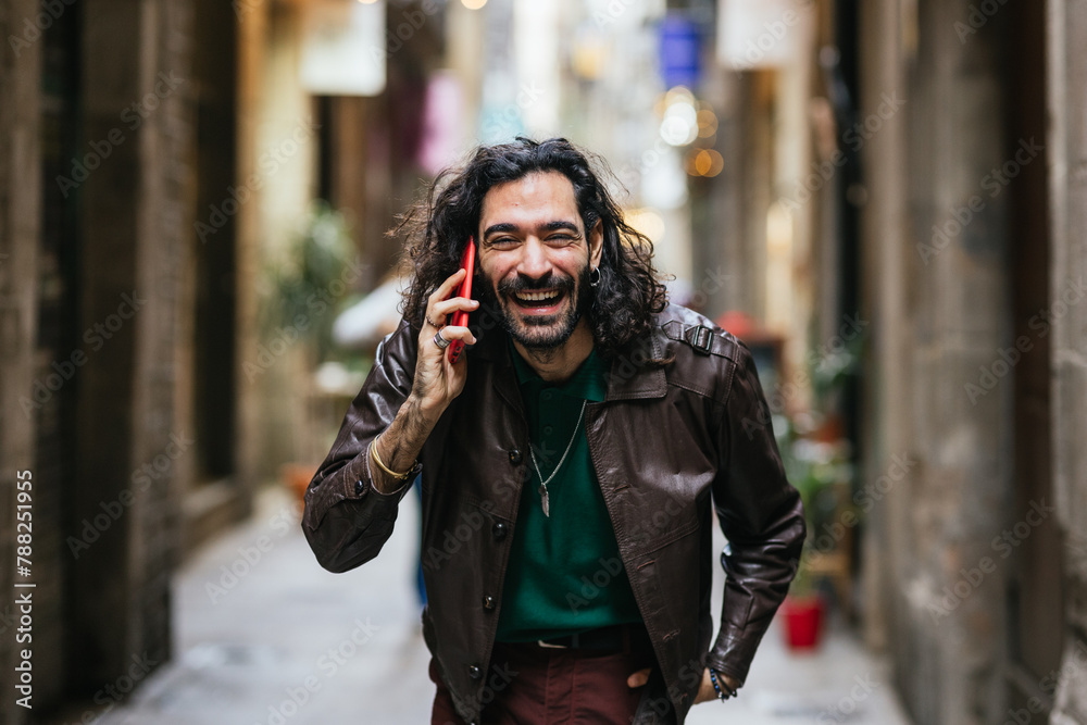 Fototapeta premium Joyful man talking on phone in urban alley
