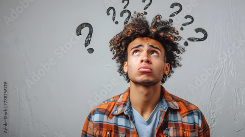 man standing looking very confused with question marks flying over his head photo