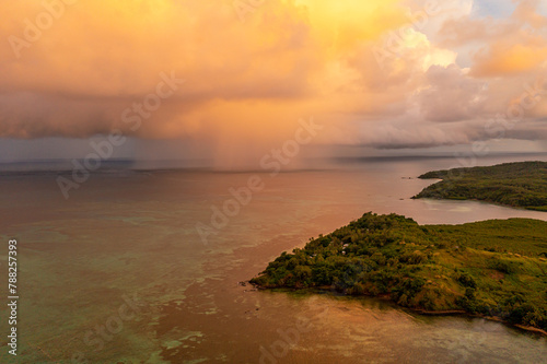Dramatic view of rain clouds over the ocean. Black and yellow clouds with rain. Sunset. Island Fiji.