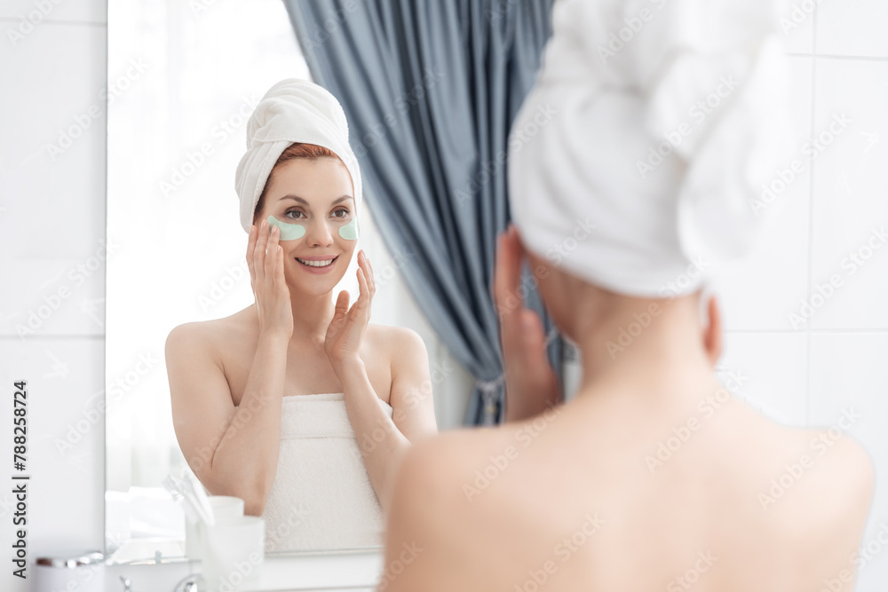 Woman wrapped in towel is examining her face in mirror, focusing on her skin, lips, eyebrows. She smiles at her reflection. Girl with towel on head takes care of her facial skin Woman wrapped in towel is examining her face in mirror, focusing on her skin, lips, eyebrows. She smiles at her reflection. Girl with towel on head takes care of her facial skin