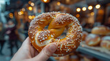 A person holding a pretzel with a blurred background.