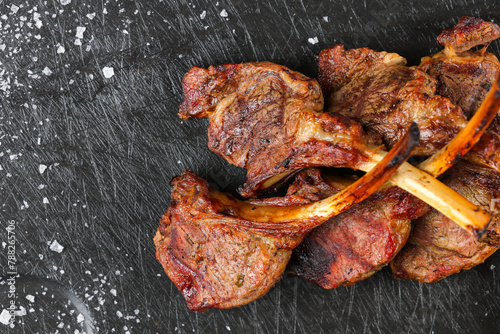 Lamb chops. Close up photo with some lamb chops grilled on barbecue and placed on a black plate with salt next to it. Lamp grill cooking.