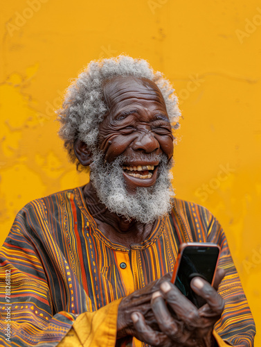 Old man fromWest Africa, laughing out loud at something he has seen on a phone. Image bringing joy.