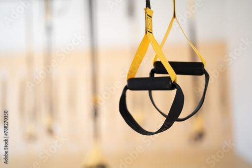 A pair of black and yellow exercise bands hanging from a ceiling
