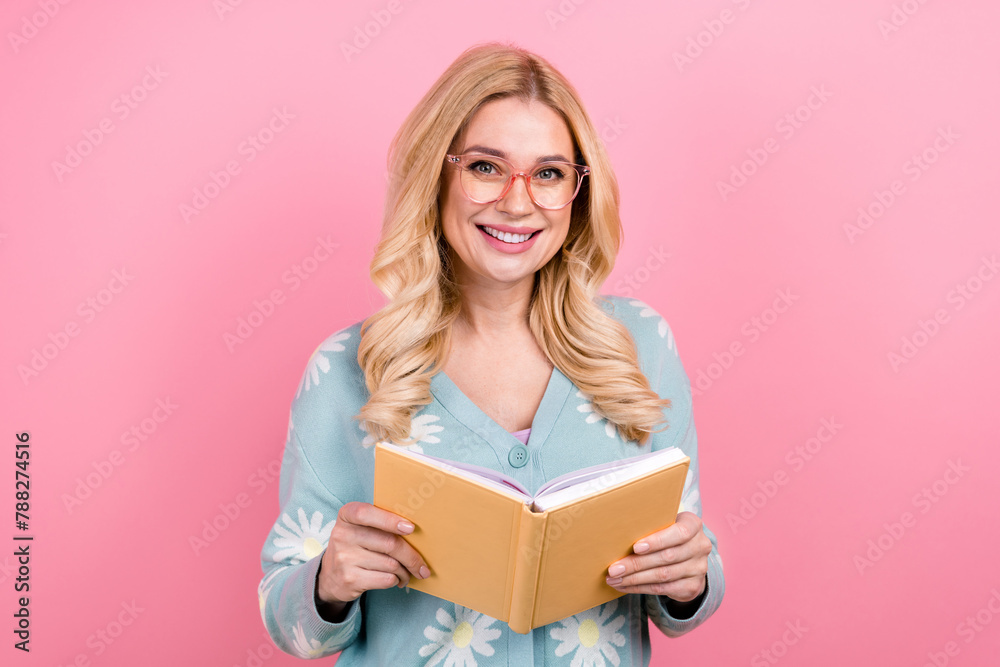Portrait of intelligent adorable person with curly hairstyle wear blue cardigan in eyewear read book isolated on pink color background Portrait of intelligent adorable person with curly hairstyle wear blue cardigan in eyewear read book isolated on pink color background