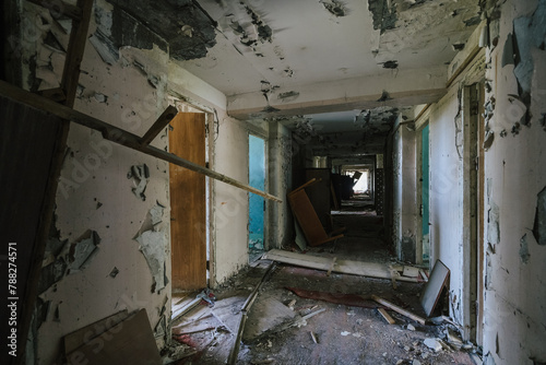 Hallway of desolation in abandoned building, peeling paint and debris speak of decay. © DedMityay