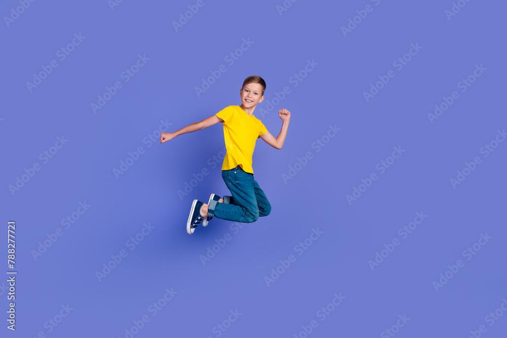 Full length photo of cheerful optimistic active boy wear stylish yellow clothes fly air yeah success isolated on violet color background