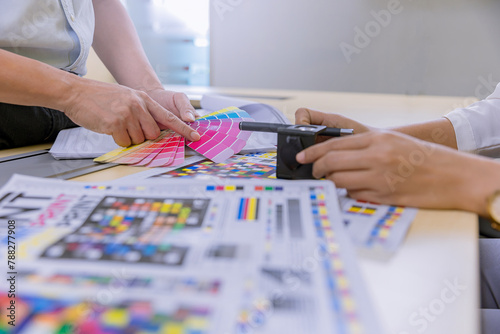 Crop image of worker checking print quality of media graphics proof print and color tone in printing industry. Selected focus