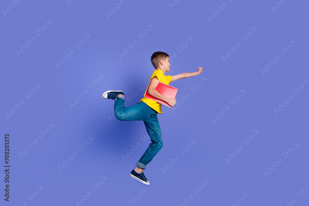 Full length photo of cheerful good mood boy wear stylish clothes hold copybooks fly look empty space isolated on violet color background