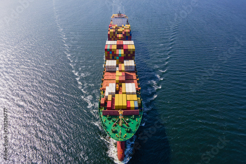 Large Container Ship carrying intermodal cargo cruising across the Sea fully loaded, Aerial view