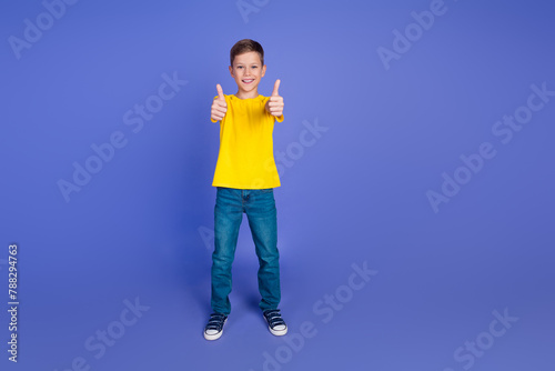 Photo of positive cheerful glad nice boy wear stylish yellow clothes thumbs up isolated on purple color background