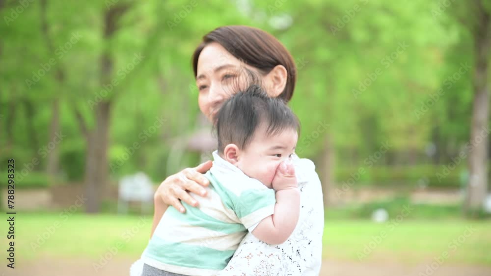 新緑の公園で赤ちゃんを抱く母親 幸せや幸福、見守り、守る母性のイメージの動画 新緑の公園で赤ちゃんを抱く母親 幸せや幸福、見守り、守る母性のイメージの動画