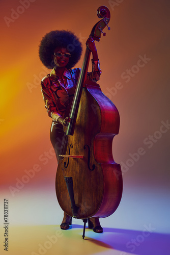 Photography Stylish African-American woman, bass player with afro in neon light against gradient background