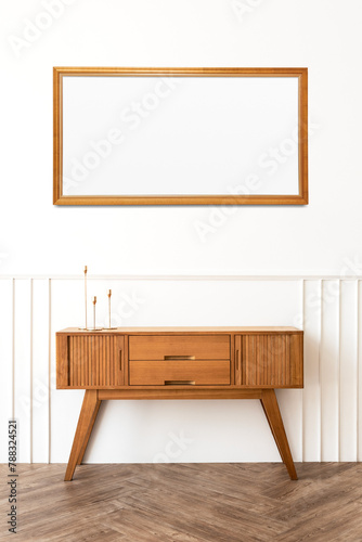 Picture frame mockup over a wooden sideboard table with taper candle holders