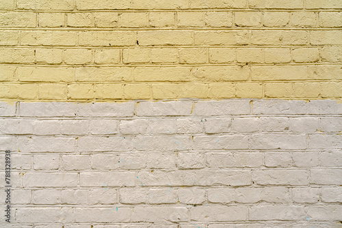 The texture of an old brick wall is painted with white and yellow paint.