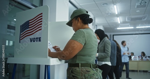 Female American army soldier votes in booth in polling station office. National Elections Day in the United States. Political races of US presidential candidates. Concept of civic duty. Dolly shot. photo