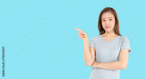 Happy excited young asian woman pointing finger to copy space imaginary to blank space for insert advertisement, happiness and smile face. Attractive beautiful girl portrait