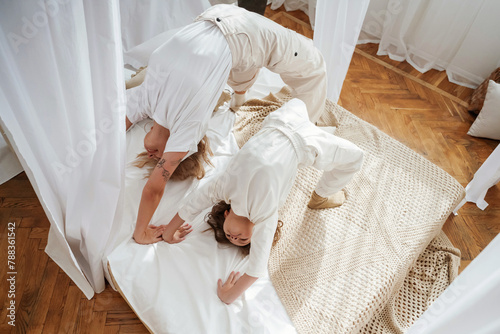 Playing in bed, standing on hands and legs. Mother with daughter are at home together