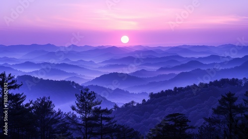 A beautiful landscape image of a mountain range at sunrise. The sky is a deep purple color, and the sun is a bright yellow orb. The mountains are covered in a blanket of fog, and the trees are a dark