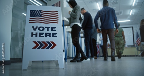 Vote here sign on the floor. Multi ethnic American citizens vote in booths in polling station office. National Election Day in United States. Political races of US presidential candidates. Civic duty. photo