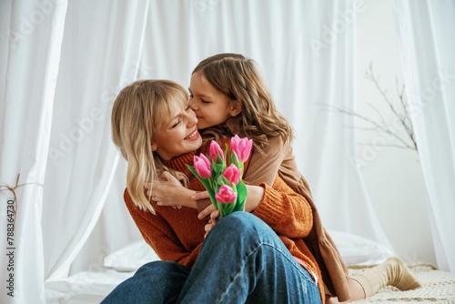 Flowers in hands. Mother's day concept. Female parent with daughter is at home