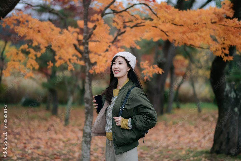 Asian woman in a vibrant dress revels in the colors of fall. A delightful and elegant portrait amid nature's changing hues. Asian woman in a vibrant dress revels in the colors of fall. A delightful and elegant portrait amid nature's changing hues.