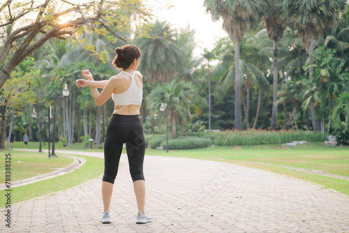 Female sportswoman. Fit young Asian woman with sportswear stretching muscle in park before running and enjoying healthy outdoor. Fitness runner girl in public park. Wellness being concept © Jirawatfoto