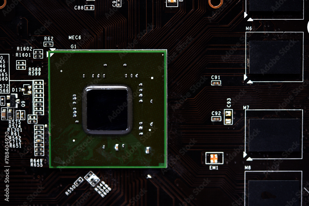 Fototapeta premium A brown printed circuit board with a processor chip and video memory strips. Electronic components on the graphics card.