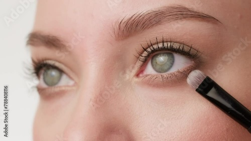 Close-up of female eyes with makeup in the process of applying eye shadow using a brush (ID: 788408116)